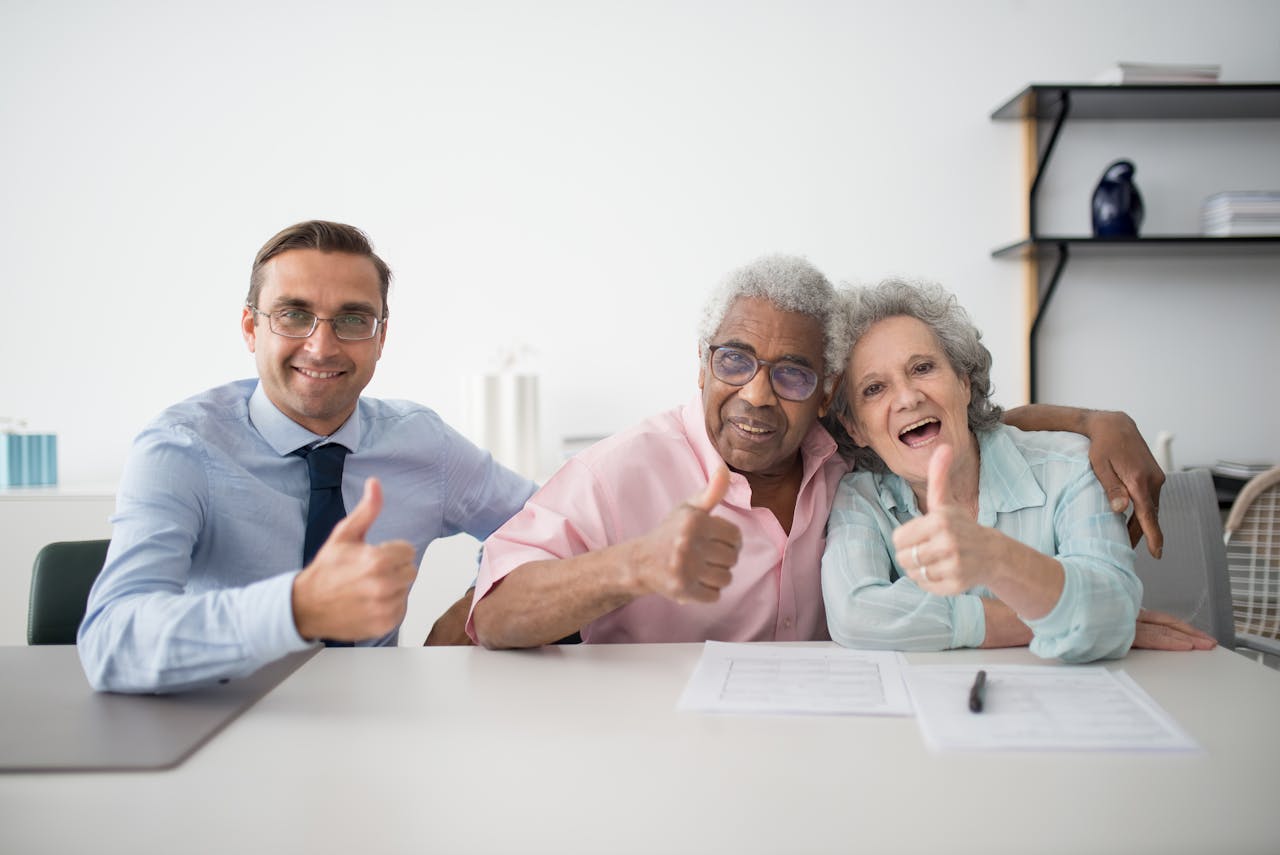 Services-01 Elderly couple with consultant giving thumbs up in an office setting, showcasing positive interaction.