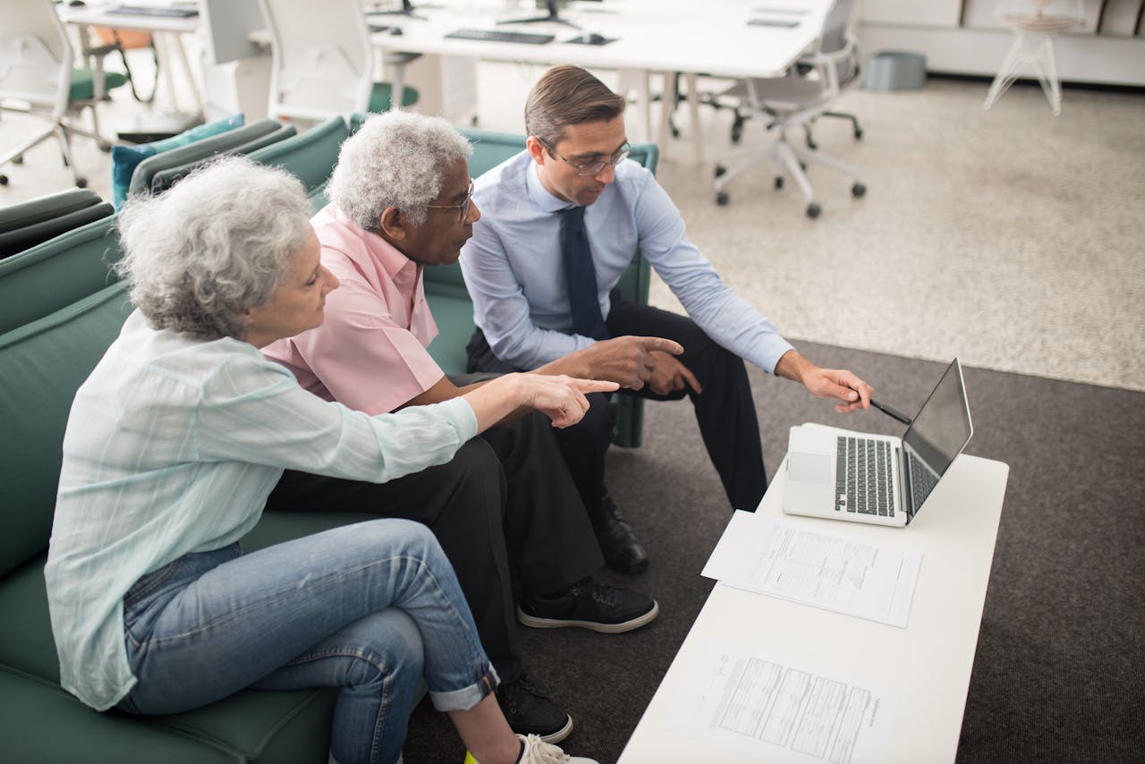 Services-03 Senior couple consulting with a professional on a laptop in a modern office setting.